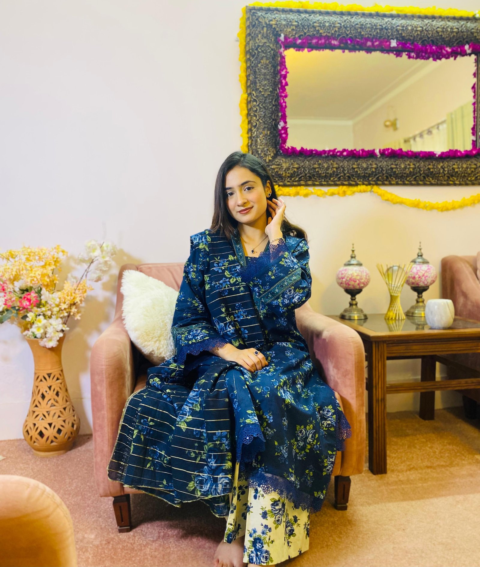 Ayesha seated in a blue floral outfit