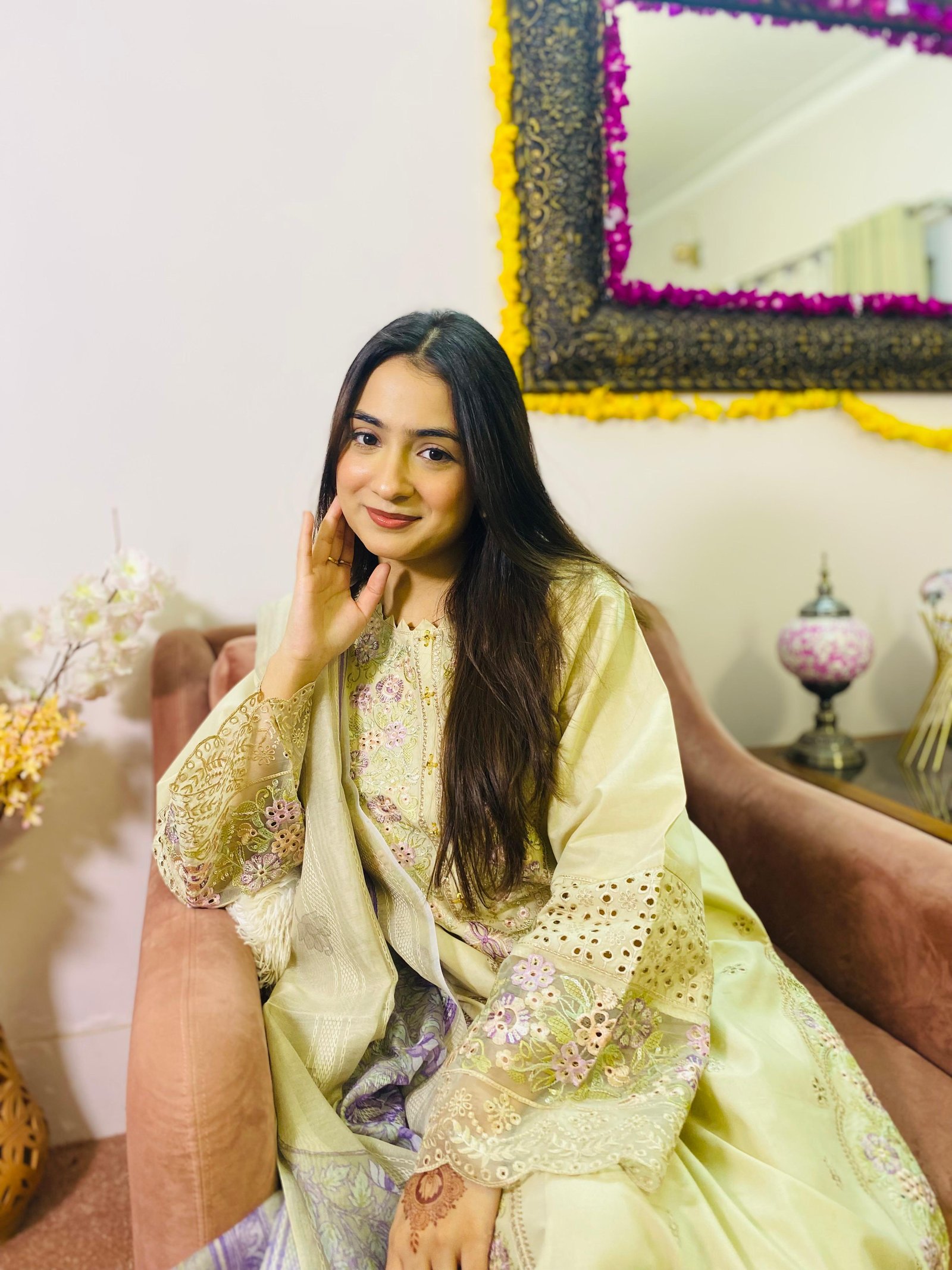 Ayesha seated in a pale yellow outfit