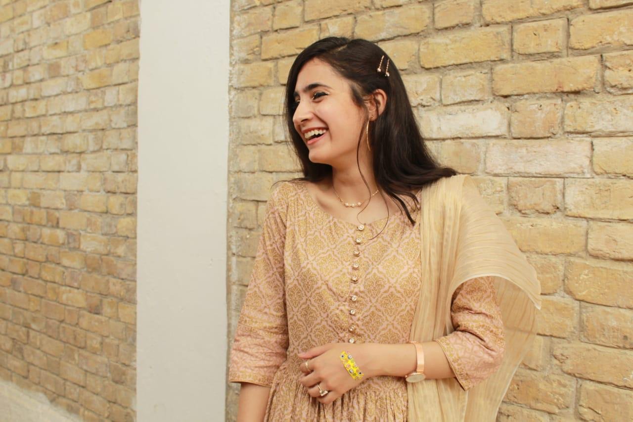 Ayesha laughing beside a brick wall